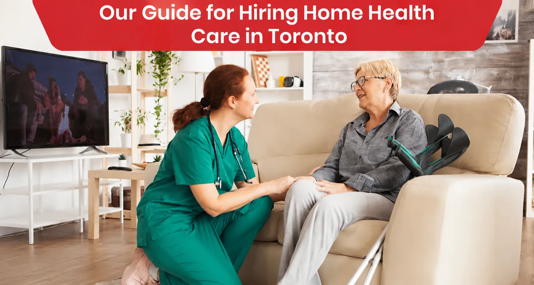 A home health nurse in green scrubs comforting an elderly woman on a sofa next to her crutches.