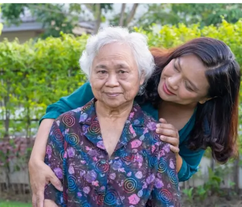 An elderly woman smiling gently while receiving compassionate home care in Etobicoke from a professional private nurse in an outdoor garden setting.