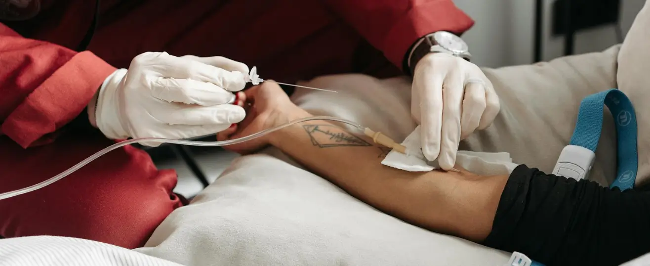 A professional caregiver from Nurse for care providing expert home nursing services by carefully administering an IV treatment to a patient in a comfortable home environment.