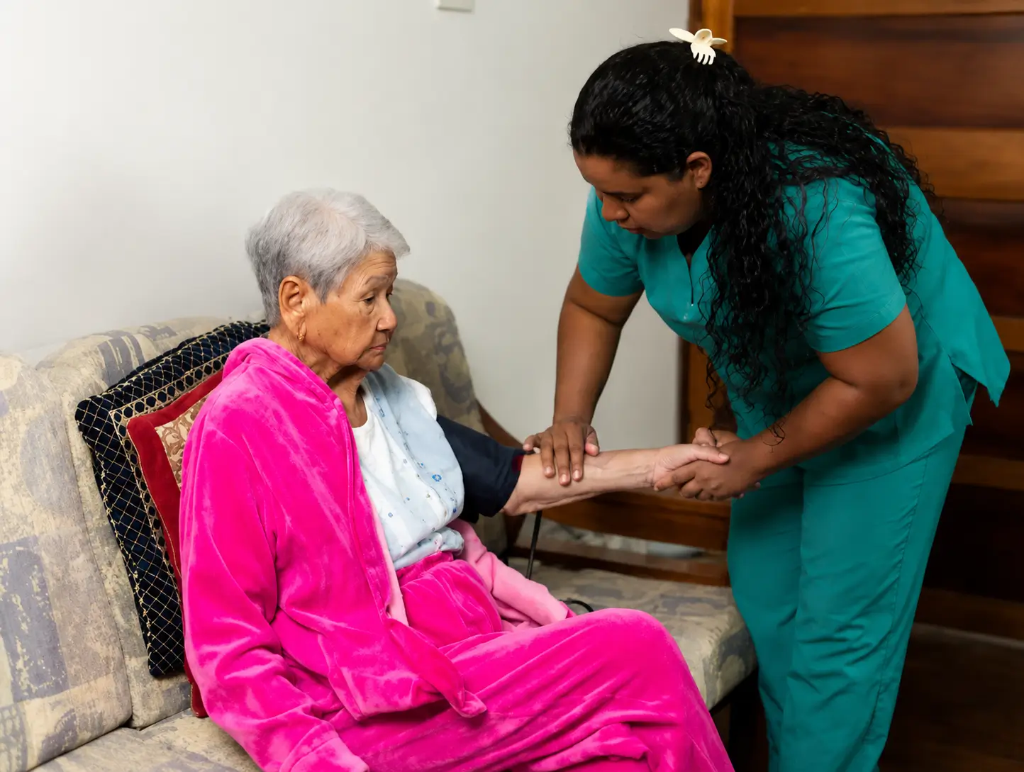 professional providing in-home nursing services in Toronto by checking the blood pressure of an elderly woman on a couch.