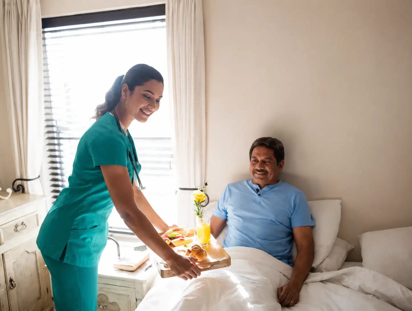 smiling personal support worker in Toronto serving a healthy breakfast tray to an elderly male patient in bed.