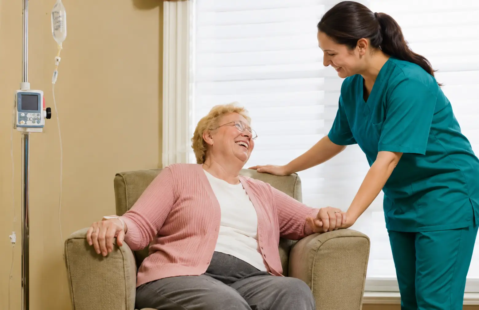 A professional female caregiver holding hands and smiling with an elderly woman seated in an armchair, illustrating high-quality live in care in Toronto.