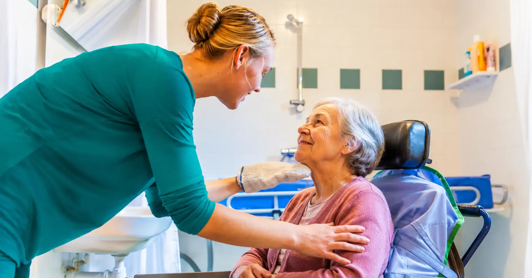 Personal Support Worker providing personal care assistance to a senior woman in a bathroom setting, offering compassionate support and daily living care.